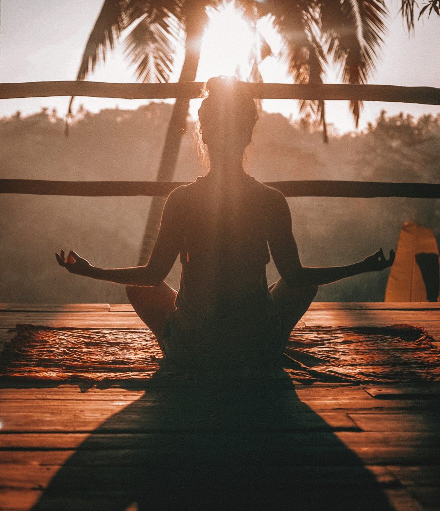 Femme de dos faisant du yoga en etant zen au soleil