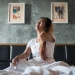 Jeune femme assise sur le lit avec douleur au cou après le réveil