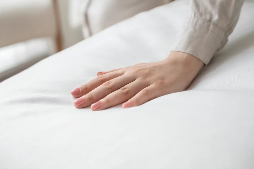 Main posée sur une couette blanche moelleuse