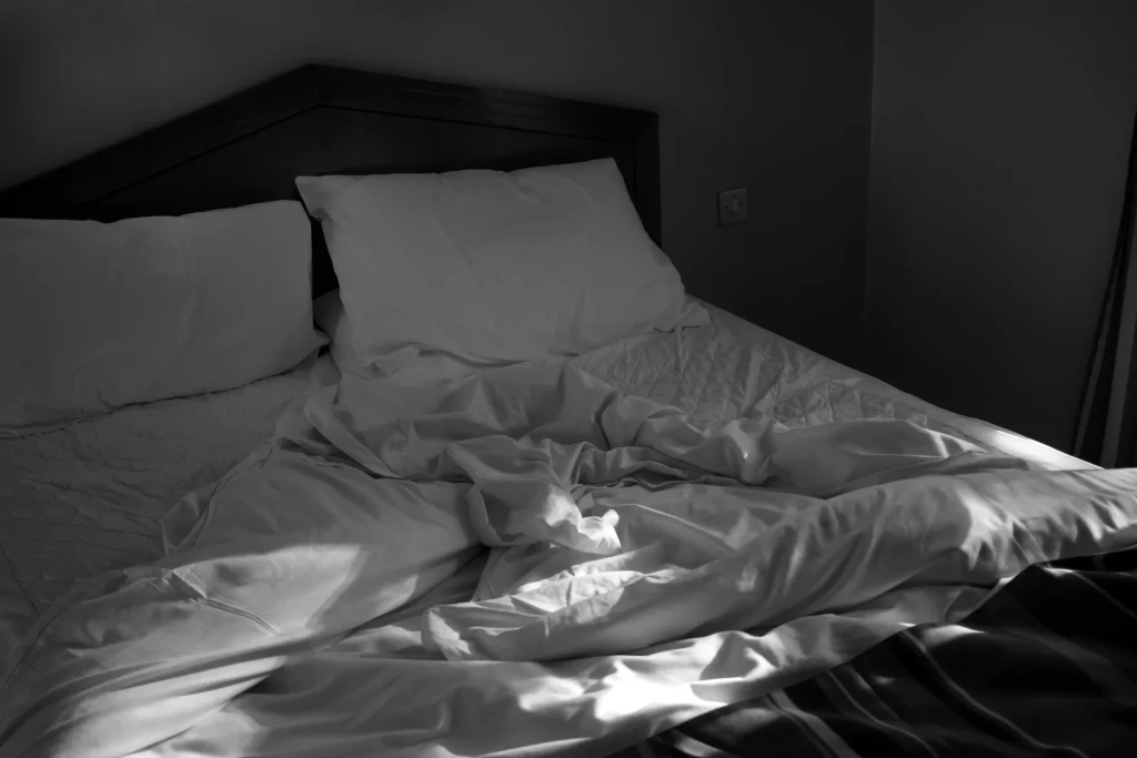 Lit défait dans une chambre avec draps froissés au lever du jour