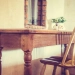 Chaise en bois devant une table rustique avec miroir et vase fleuri.
