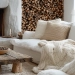Salon cocooning avec cheminée allumée, plaid en laine épaisse et coussins beiges sur un canapé confortable.