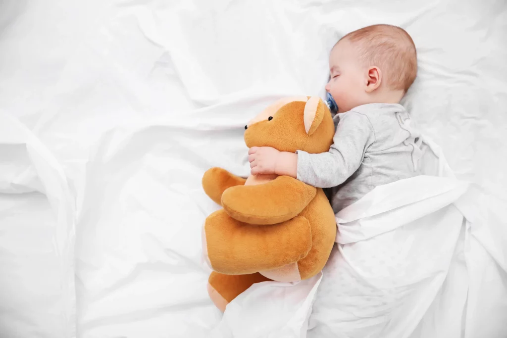 Bébé qui dort dans son lit avec sa peluche