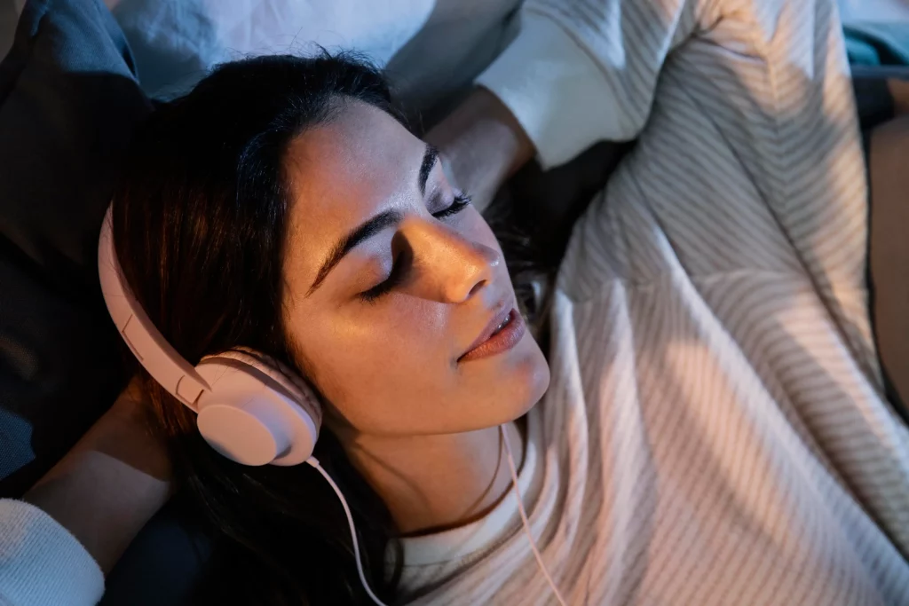 Femme utilisant des écouteurs pour la musique à la maison dans le lit
