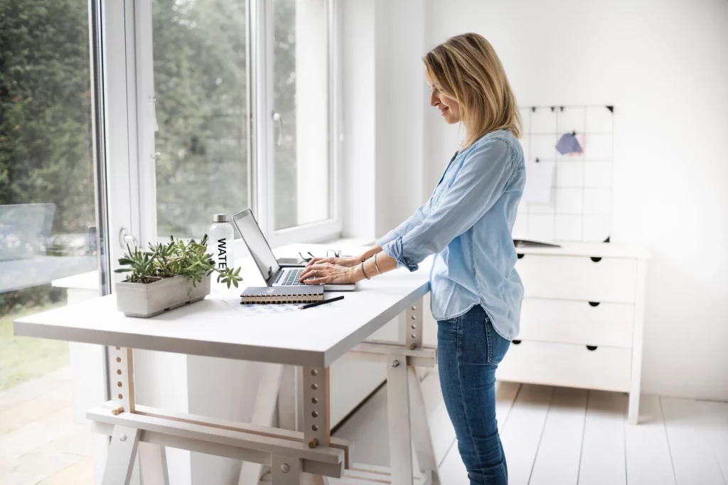 Vue latérale d'une femme debout utilisant un ordinateur portable à la maison
