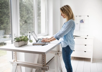 Vue latérale d'une femme debout utilisant un ordinateur portable à la maison