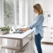 Vue latérale d'une femme debout utilisant un ordinateur portable à la maison