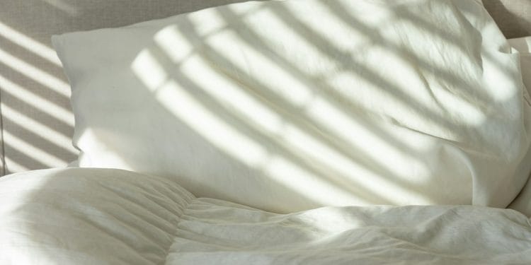 Lit fait, garni d'une couette et d'oreillers blancs