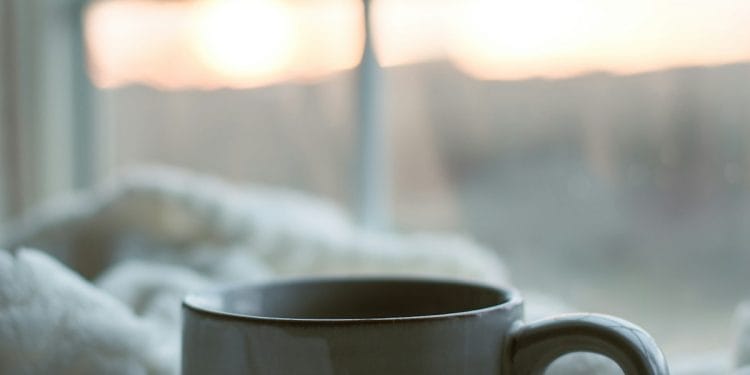 Tasse de café posée sur une couverture blanche au réveil