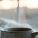 Tasse de café posée sur une couverture blanche au réveil